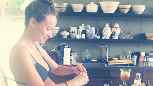 Olivia Wilde shows off her bare baby bump while cooking in a bikini