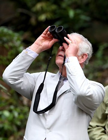 King Charles holds up binoculars