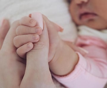 Baby holding its mother's thumb