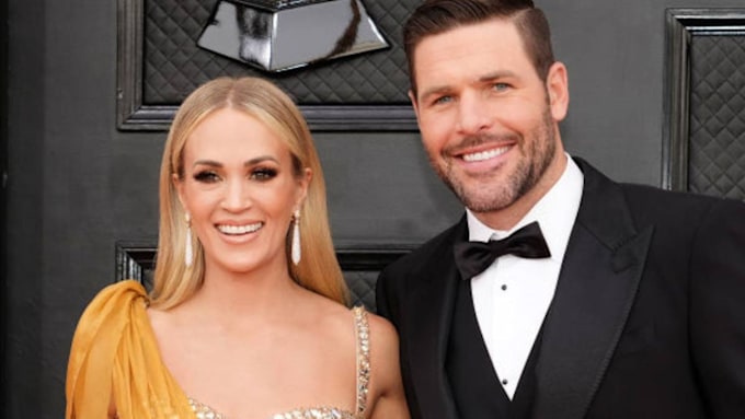 Carrie Underwood smiles with her husband by her side at an awards ceremony 