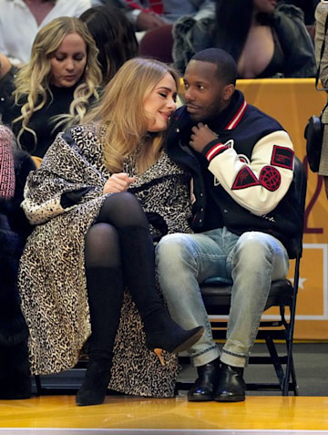 Adele leans into Rich Paul during a basketball game