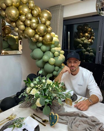 Jack Grealish posing at his dining table next to a balloon arch