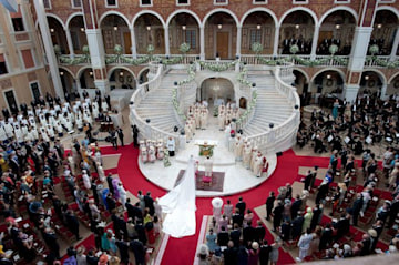 a photo taken from a rooftop overlooking a courtyard which is filled with people facing towards a white marble staircase and red carpet has been placed around the botton steps