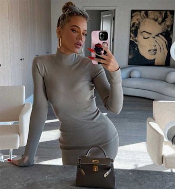 Khloe Kardashian poses in the mirror wearing a silver dress