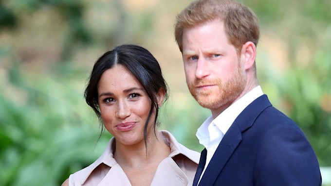 prince harry looking stern and meghan markle smiling
