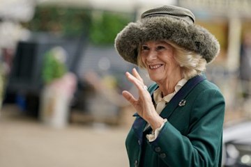 Queen Consort Camilla waving in a green coat and fur hat