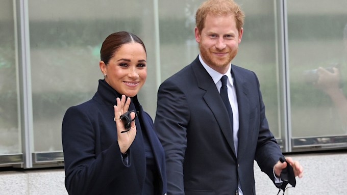 meghan markle and prince harry dressed all in black as they smile and wave