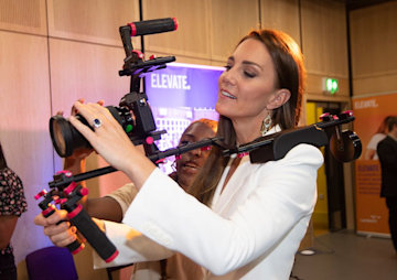 Kate Middleton in a white suit using a serious camera 