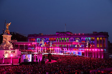 Buckingham Palace lit up with portraits of the Queen