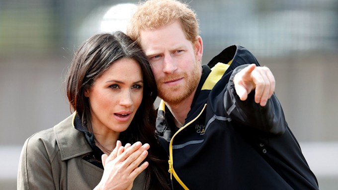 Prince Harry pointing into the distance with Meghan Markle next to him