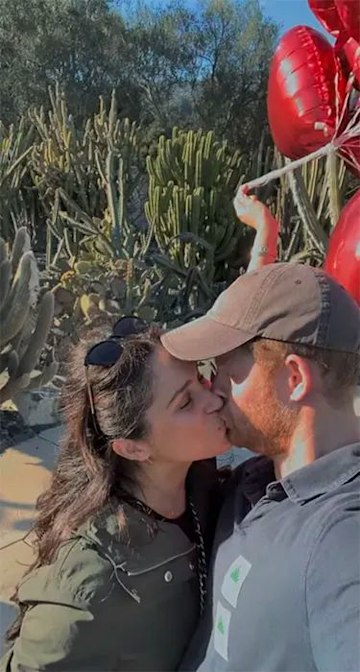 Meghan Markle and Prince Harry share a kiss as they hold heart-shaped balloons